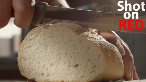 Male Holding A Crusty Bread Load And Cutting A Piece With A Knife In Slow Motion Shot On Red Camera