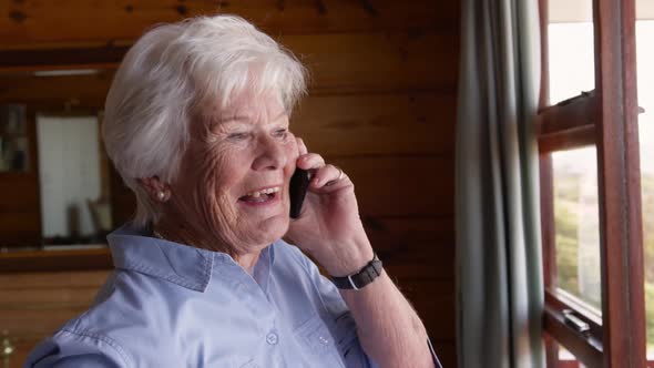 Woman talking on mobile phone in bedroom at home 