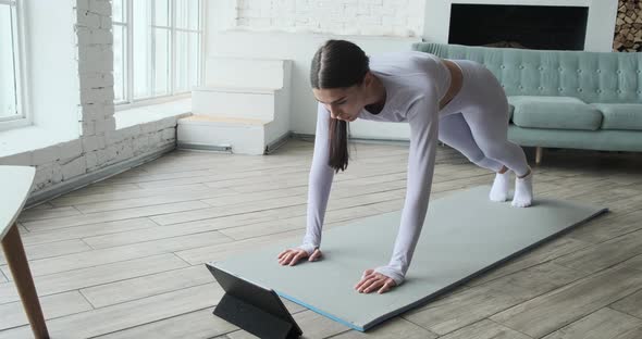 Athletic Young Woman Watching Video Tutorial on Tablet Doing Exercises