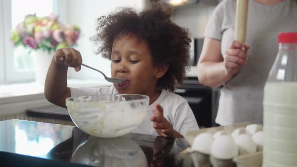 Family Baking  Black Little Girl Eating the Rests of a Liquid Dough From the Bowl