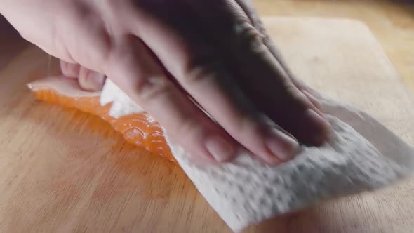 Close Shot of Patting the Fish Skin Dry on a Salmon Fillet Prior to Cooking in the Kitchen