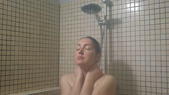 Portrait of Young Woman Taking a Warm Shower Enjoying Process with Close Eyes.