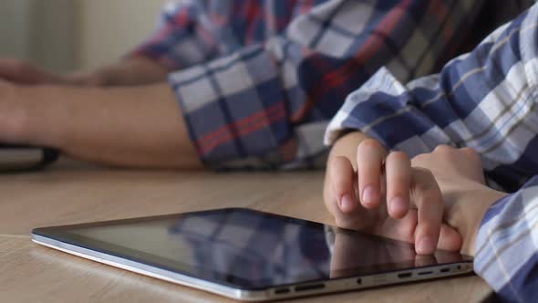 Obedient Child Playing Mobile Game on Tablet While Father Working on Laptop