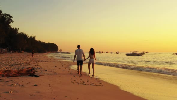 Beautiful young couple in love walking along the beach while the waves flood the beach enjoying the