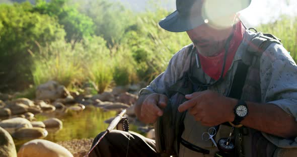 Fly fisherman preparing string to tie on hook