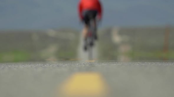 A man road biking on a scenic desert road.