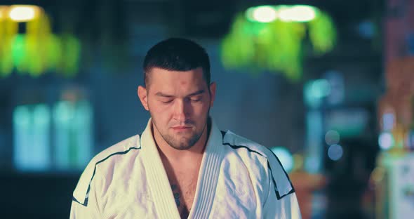 Serious Male Fighter in a White Kimono Looks at the Enemy Before the Battle