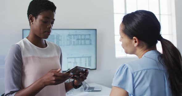 Two diverse businesswoman working and talking in office