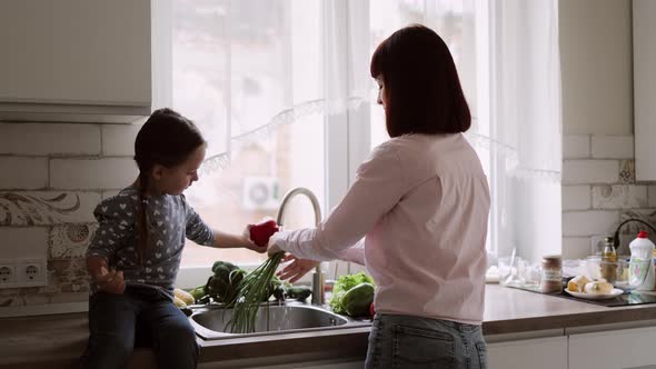 Little Girl Helping Her Muslim Mother Washing Vegetables in the Kitchen