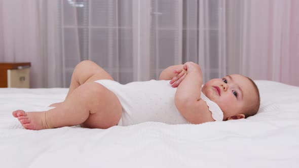 Beautiful Smiling Baby A Gorgeous Little Baby Lies on the Bed