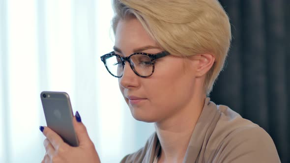 Charming Joyful Female Is Reading Pleasant Text Message on Mobile Phone From Her Boyfriend During