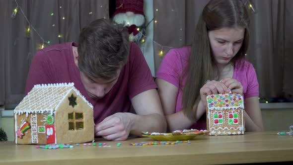 A Guy and a Girl Decorate a Christmas Gingerbread House