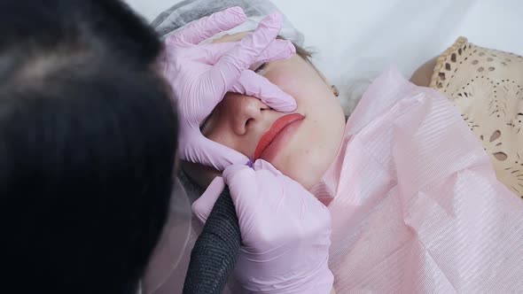 Young Woman Having Permanent Makeup on Lips in Beautician Salon