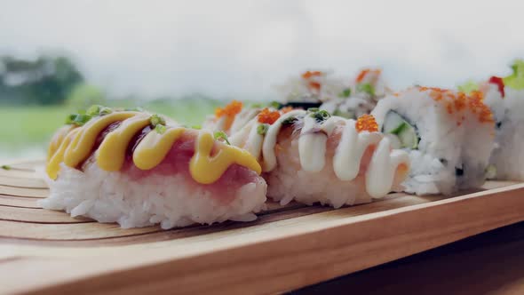 Closeup of a Man Taking Sushi Sticks with Salmon From a Wooden Stand