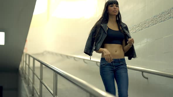 4K Portrait of Stylish Hispanic woman walking down cross street tunnel in the city at night.