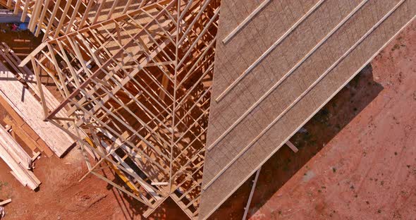 Aerial Top View of Construction Working on the Roof Beams of Under Construction Wooden Built Home