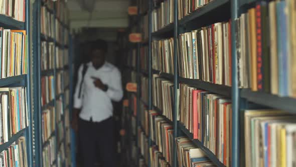 Blonde Teacher Searching Book in the Library in School