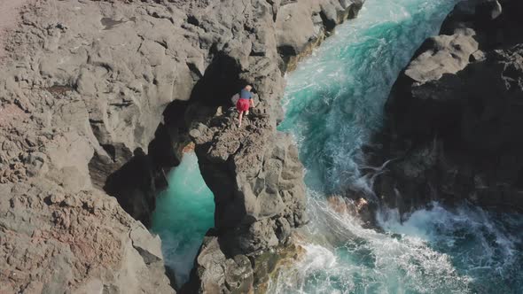 Man Walks Along the Lava and Fossil Cliff As Seen From Top