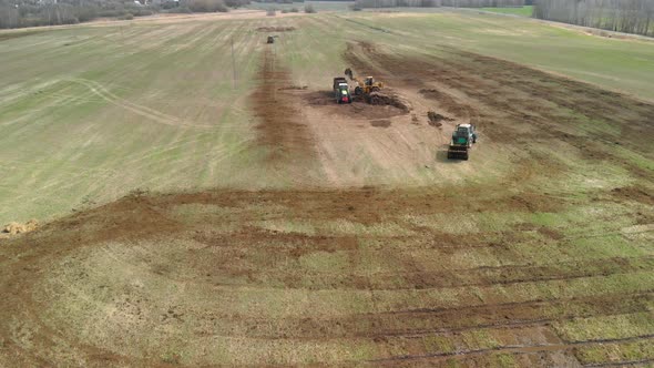 Loader Fills the Tractor's Manure Spreader in the Field