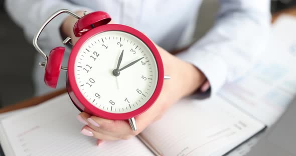 Business Woman Setting Time on Alarm Clock in Office Closeup