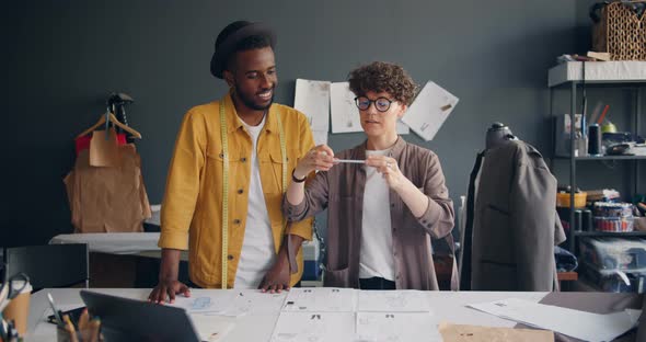 Couple of Designers Shooting Flat Lay Taking Photo of Sketches on Sewing Table