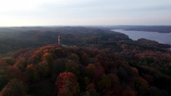 Drone Over Dense Forest With Tower On Hill