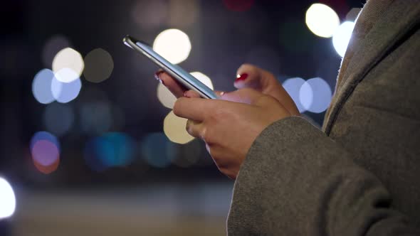 Female Hands Using Smartphone on Blurred City Lights Background