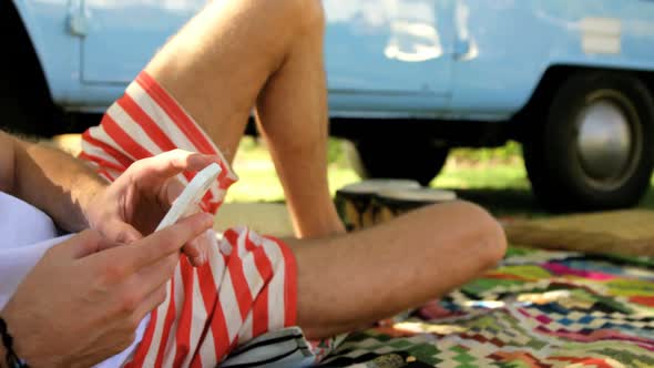 A hipster man lying and texting on his smartphone