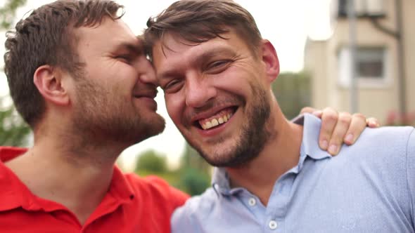 Portrait of Young Gay Couple Embracing and Showing Their Love with Rainbow Flag at the Street. LGBT