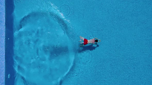 View From the Top As a Man Dives Into the Pool and Swims Under the Water