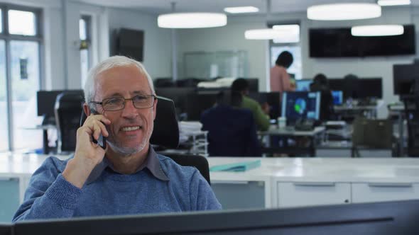 Man talking on smartphone while sitting on his desk at office