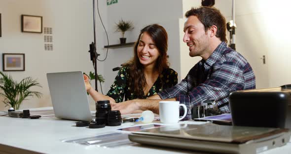 Photographers discussing over laptop at desk