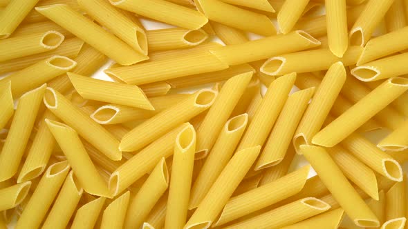 Uncooked penne pasta rotating top view