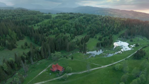 Aerial View of a Mountain Landscape with a House and a River in the Foreground and Rocks Covered By