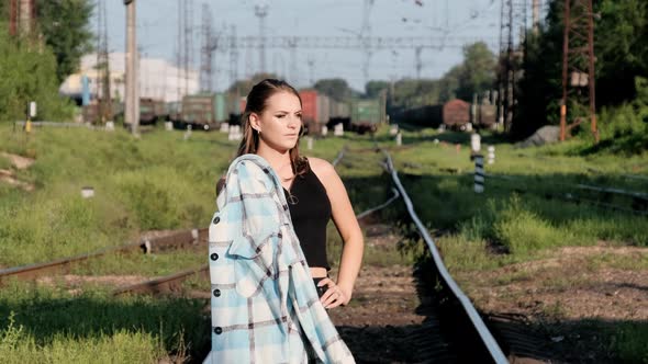 Young Sexy Woman Stands on the Train Tracks and Looks at the Camera