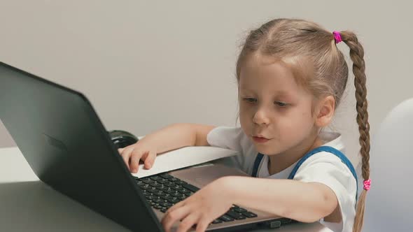 Slow Motion Little Girl Sits at Table with Notebook