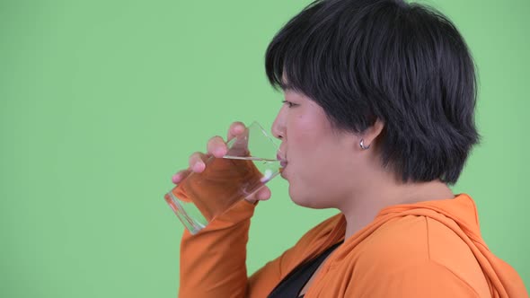 Closeup Profile View of Happy Young Overweight Asian Woman Drinking Water Ready for Gym