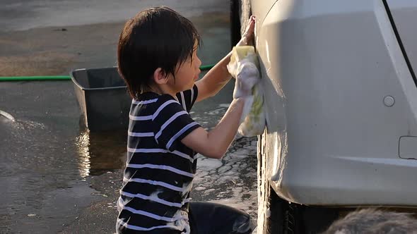 Asian Child Washing Car In The Garden With Dog On Summer Day