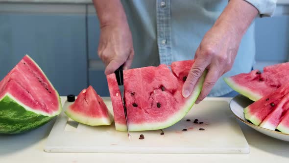 Man in Home Kitchen While Cutting a Ripe Red Watermelon in Slices