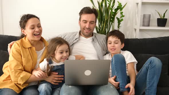 Family of Four Using Laptop for Video Connection with Grandparents or Family