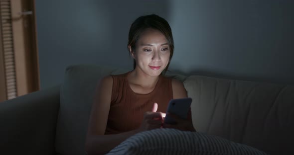 Woman use of mobile phone at home in the evening