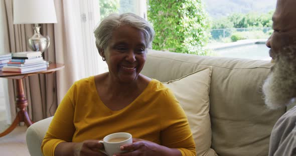 Senior african american couple talking and drinking tea in living room at home