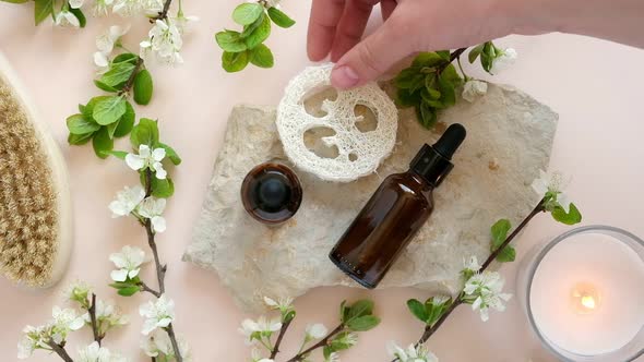 Female Hand Holding Serum Bottle Over Beige Table