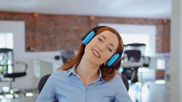 Redhead Businesswoman Listening Music at Work