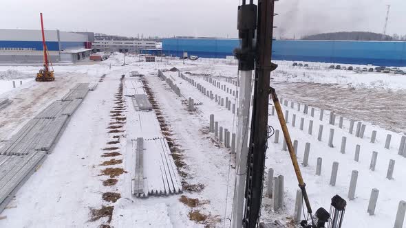 Close-up aerial drone view of a pile bore machine at work at winter construction site 25