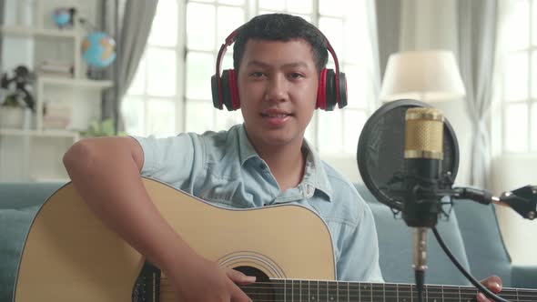 Asian Boy Vlogger With Guitar. The Child Is Broadcasting Live On The Internet