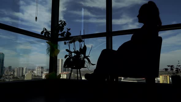 Silhouette of a Young Woman Looking Out The Window