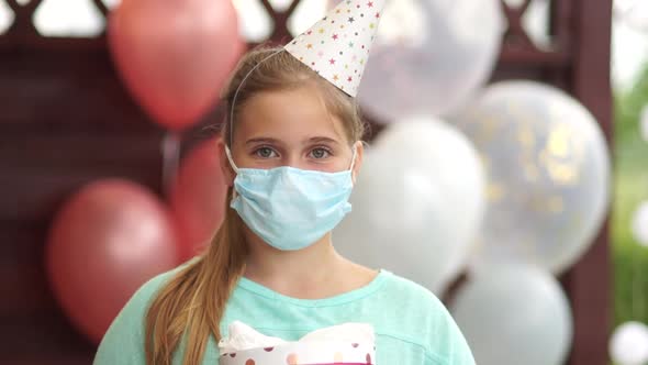 Close Up Portrait of a Sad Teenage Girl Wearing a Birthday Cap and a Protective Mask