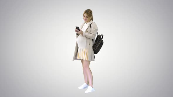 Pregnant Casual Woman Holding Cellphone Texting a Message on Gradient Background