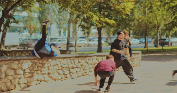 Young Guys Run Through the Park and Do a Somersault with a Coup Parkour